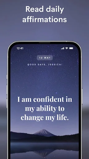 Daily affirmations app displaying 'I am confident in my ability to change my life' with peaceful mountain lake background
