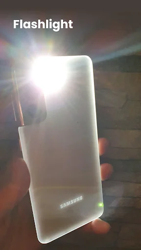 Samsung smartphone with bright white LED torch fully activated, producing intense lens flare and maximum brightness